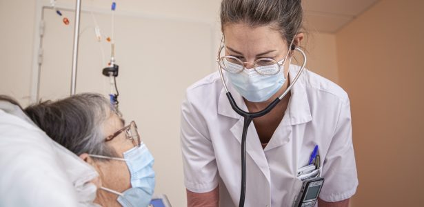 Une médecin penchée sur une patiente dans un environnement hospitalier