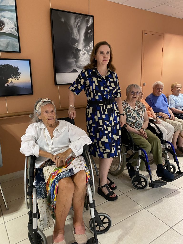 Florence Quiviger, directrice de l'établissement de Baguer-Morvan, entourée de résidents devant l'exposition de Mathieu Rivrin.